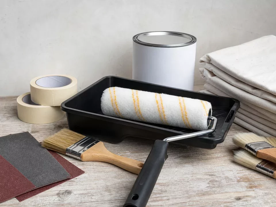Rodillo, brochas, bandeja y accesorios de pintura ordenados en una mesa